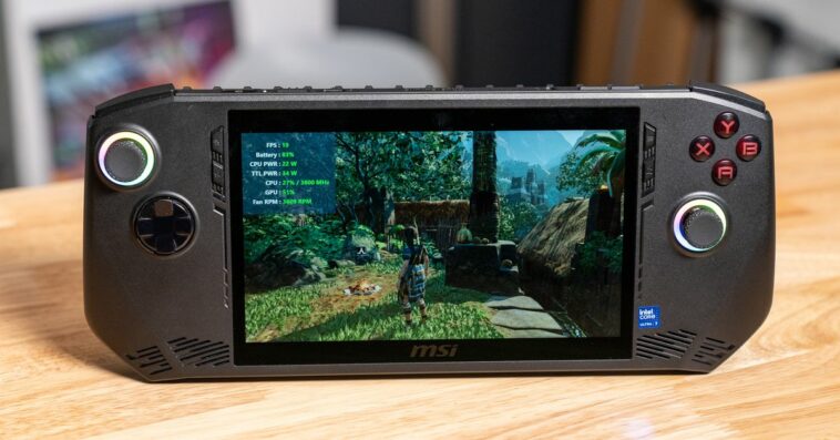 A black wide handheld gaming PC with rainbow rings around its black joysticks and Tomb Raider on the screen.