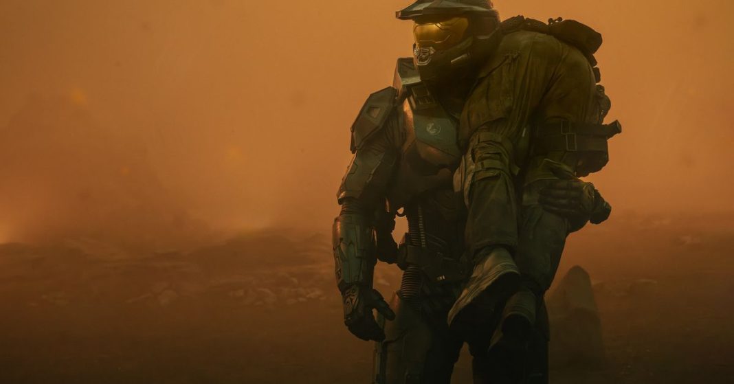 Screenshot from Halo season 2 episode 1 “Sanctuary” featuring Master Chief carrying a wounded soldier against a yellow-orange background