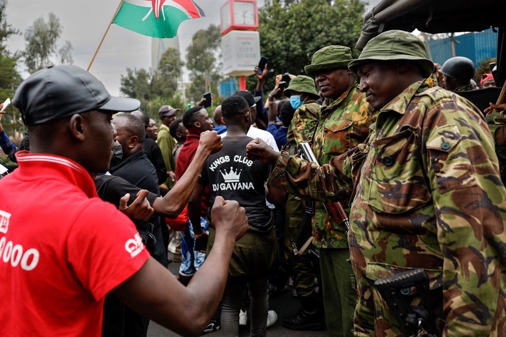 Kenyan youths gestures at policemen as they march in memory of protesters killed during the nationwide deadly protest against a controversial now-withdrawn tax bill that left over 20 dead and shocked the East African nation, in Nairobi on 30 June 2024. (Simon Maina/AFP)