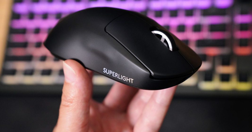 A hand holds up a jet black sculpted plastic mouse with a white scroll wheel and white words “Superlight” printed on the side.