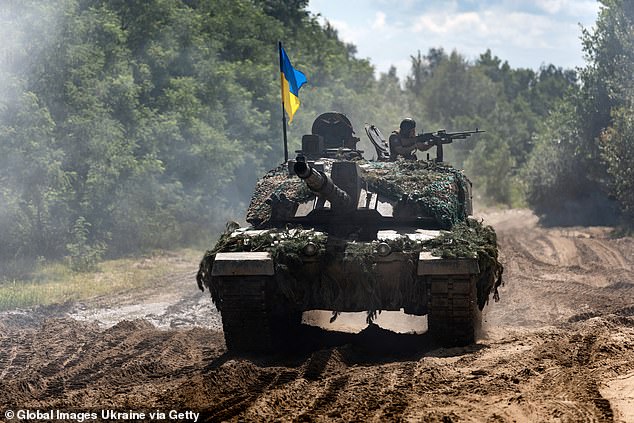 Un soldado ucraniano con una ametralladora en sus manos viaja por un camino de tierra en un tanque Challenger-2 el 3 de agosto de 2023 en Ucrania.