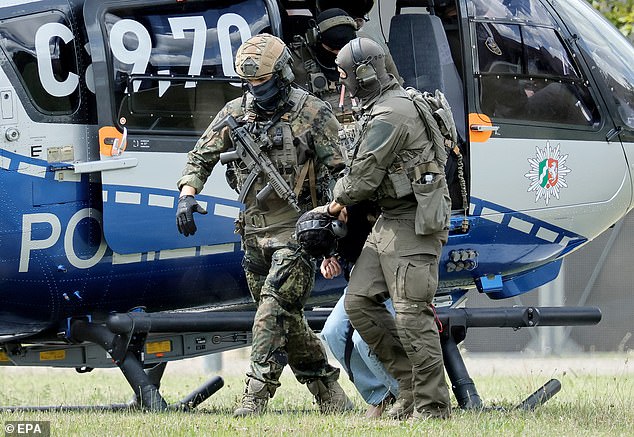 El sospechoso (en la foto, en el centro) fue visto siendo arrastrado a su comparecencia ante el Tribunal Supremo Federal (BGH) en Karlsruhe, Alemania, hoy por agentes de la policía federal.