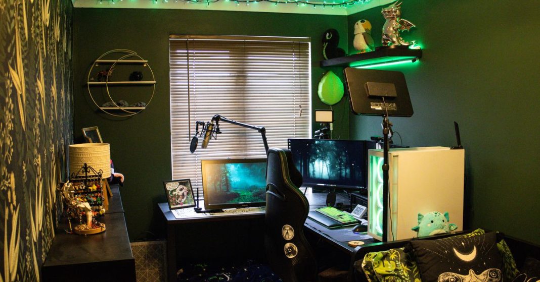 Home office with corner desk, green highlights, and a windows with blinds down.