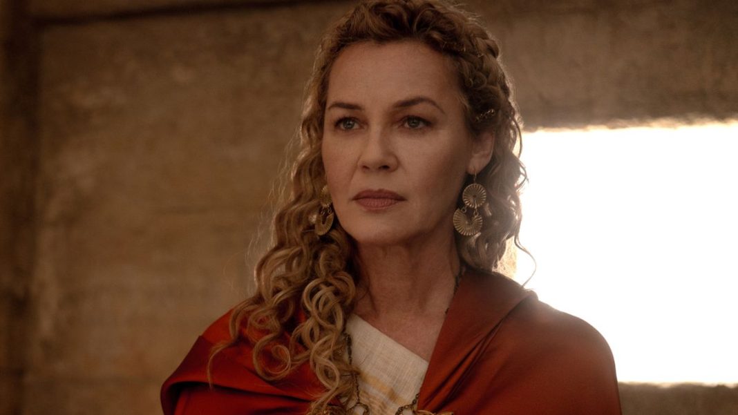 Connie Nielsen stands in a room looking regal with a red cloak in Gladiator II.