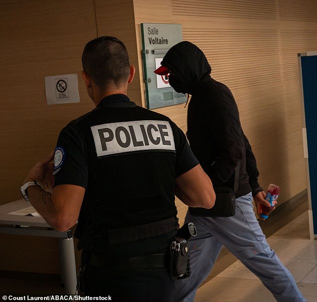 Un acusado llega a la sala del tribunal el 20 de septiembre acompañado de un oficial de policía.