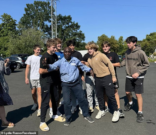 Francis Apraku, un conserje (centro) de la escuela secundaria James Madison en Vienna, Virginia, se quedó sin palabras después de que los estudiantes se unieron para darle un regalo de cumpleaños el lunes.