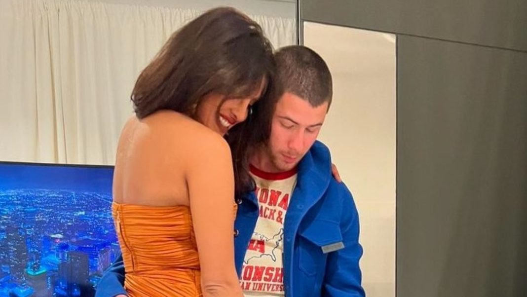 Priyanka Chopra le da un beso de cumpleaños a Nick Jonas durante su concierto en Londres, Malti Marie asiste con auriculares puestos.
