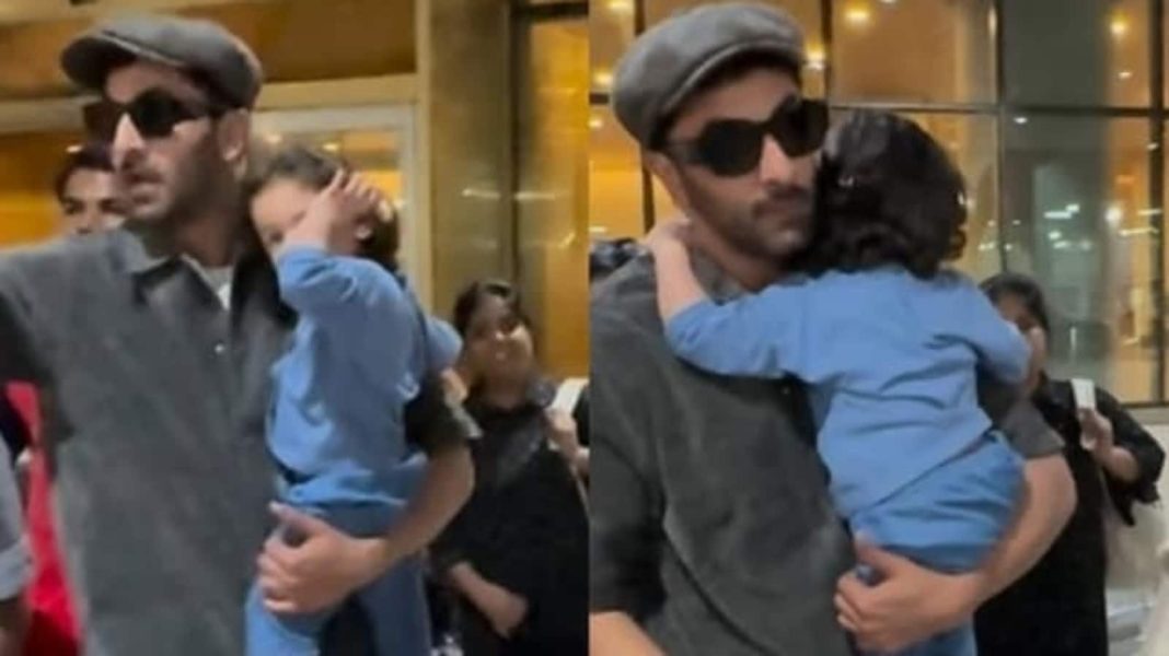 Raha Kapoor se frota los ojos y abraza a su padre Ranbir Kapoor mientras los paparazzi usan flashes de cámara
