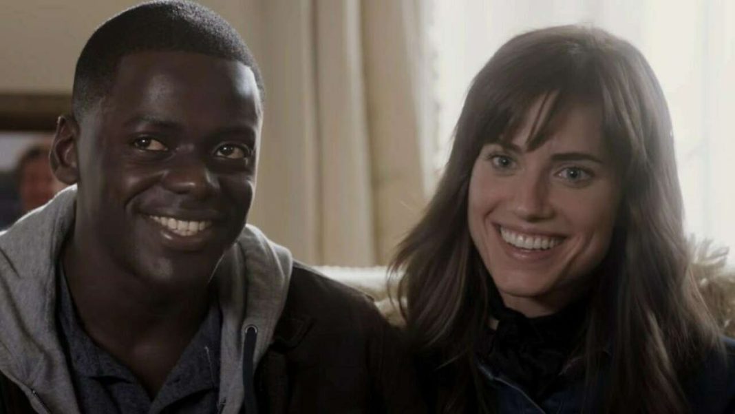 Daniel Kaluuya and Allison Williams sitting next to each other on a bed and smiling uncomfortably in Jordan Peele&#039;s 2017 hit, &quot;Get Out.&quot;