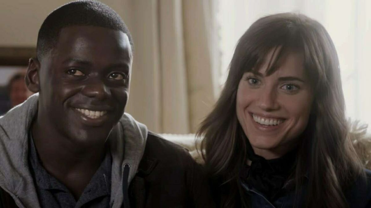 Daniel Kaluuya and Allison Williams sitting next to each other on a bed and smiling uncomfortably in Jordan Peele's 2017 hit, &quot;Get Out.&quot;