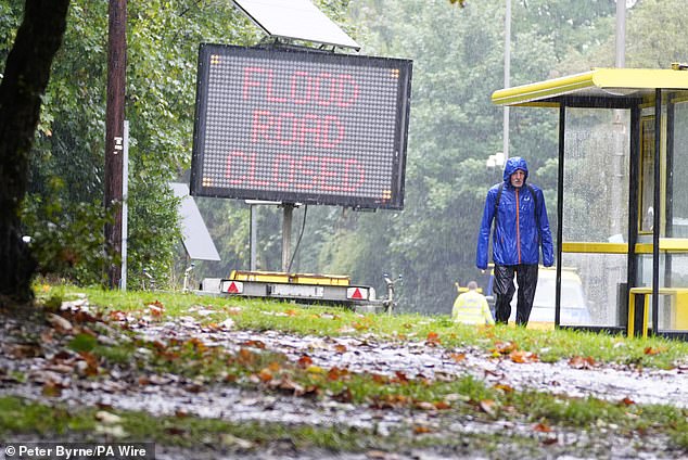 LIVERPOOL: Un hombre empapado con un impermeable pasa junto a una señal de tráfico inundada el 1 de octubre, mientras se pronostica que tormentas eléctricas azotarán el centro y sur de Inglaterra y Gales el lunes.