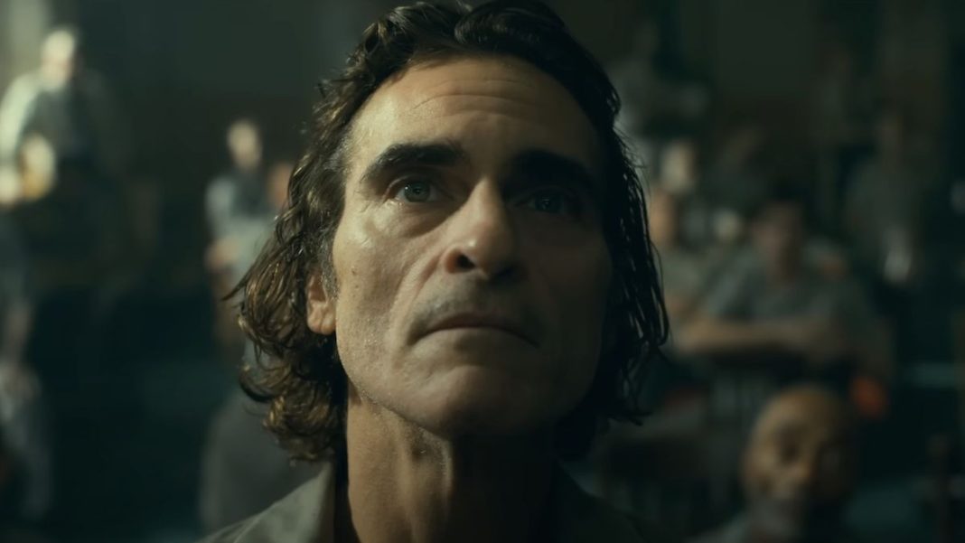 Screenshot of Arthur Fleck looking up at TV in jail in Joker: Folie à Deux