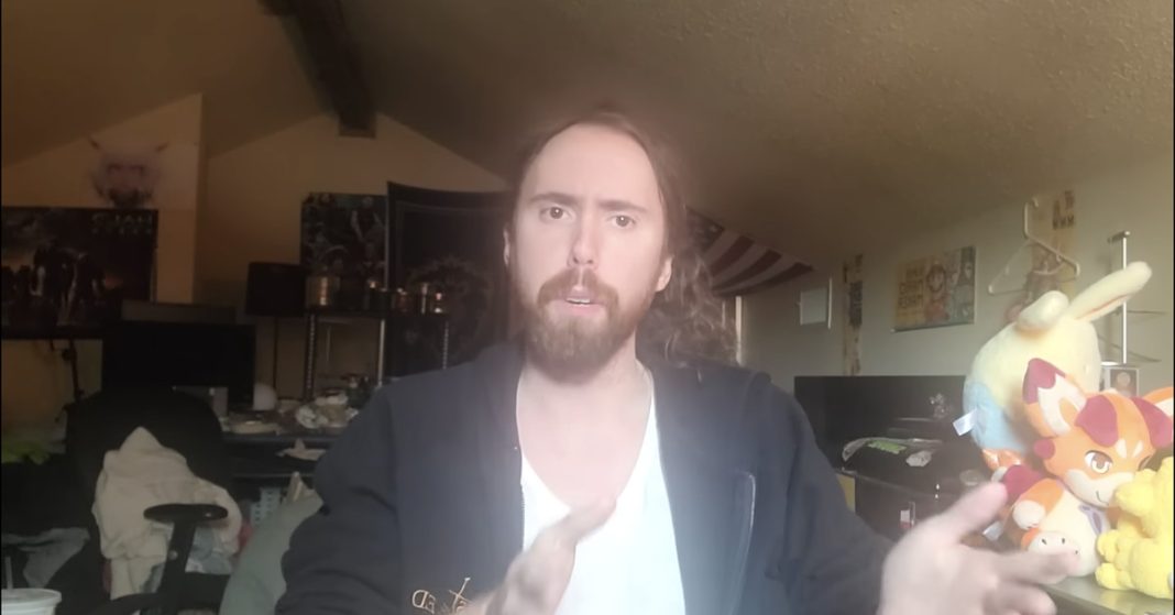 Screenshot from an Asmongold video featuring a white male in a white shirt and black sweater looking into the camera.