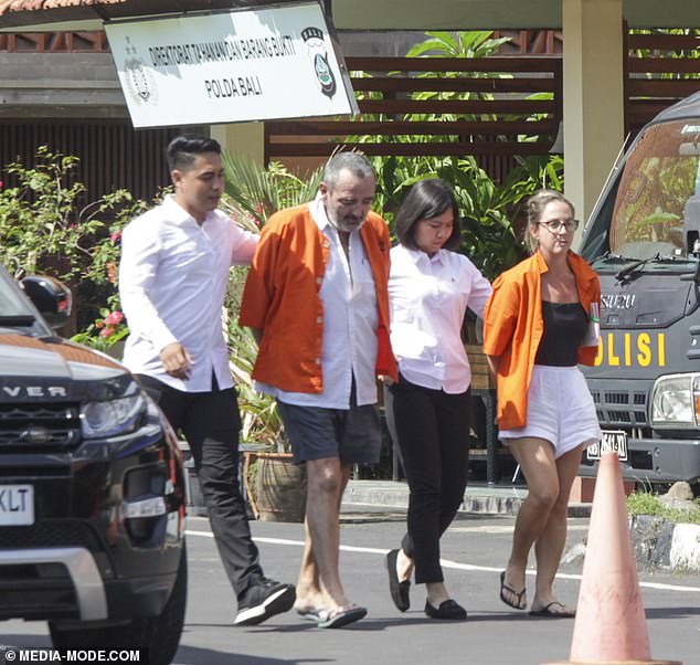 Con la cabeza inclinada, Michael Le Grand y su esposa Lynley desfilan esposados ​​frente a la sede de la policía de Bali después de su arresto.