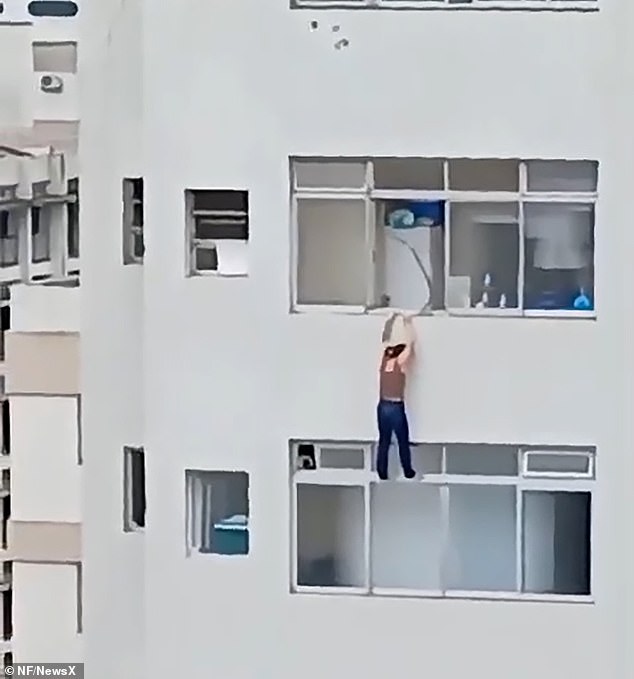 Este es el dramático momento al que una mujer se aferra por su vida mientras cuelga de la repisa de un bloque de apartamentos de gran altura después de resbalarse mientras limpiaba las ventanas.