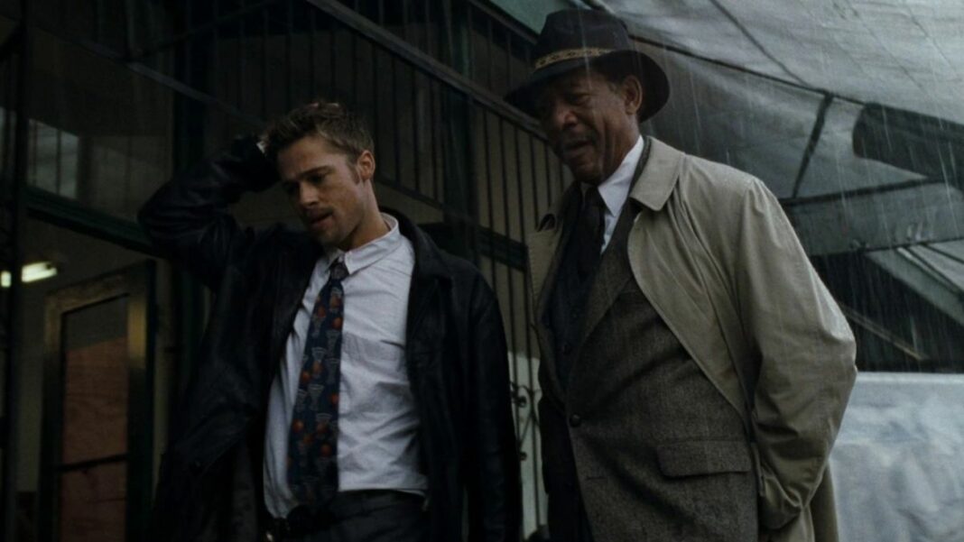 Brad Pitt and Morgan Freeman standing in the rain while on the hunt for John Doe in Se7en.