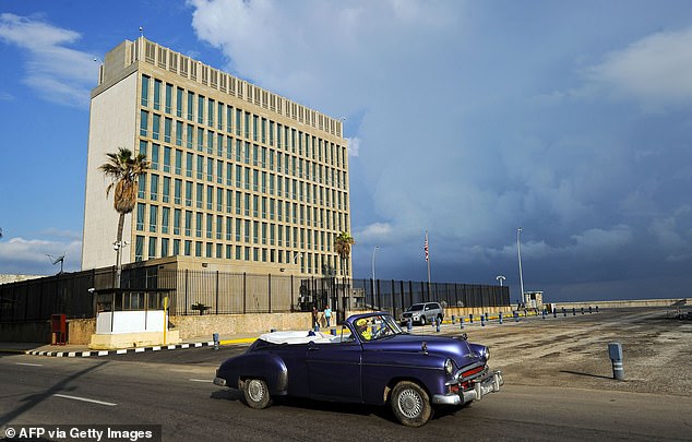 Arriba, un viejo automóvil estadounidense pasa por la embajada de Estados Unidos en La Habana el 17 de diciembre de 2015.