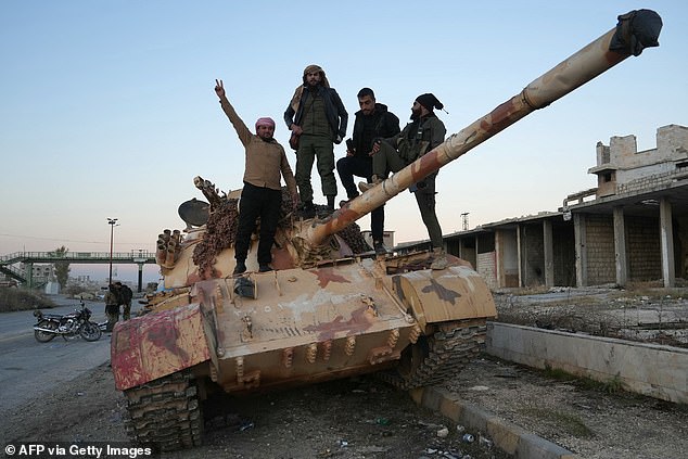 Los combatientes antigubernamentales posan para una fotografía en un tanque en la carretera que conduce a Maaret al-Numan en la provincia de Idlib, al noroeste de Siria, el 30 de noviembre de 2024.