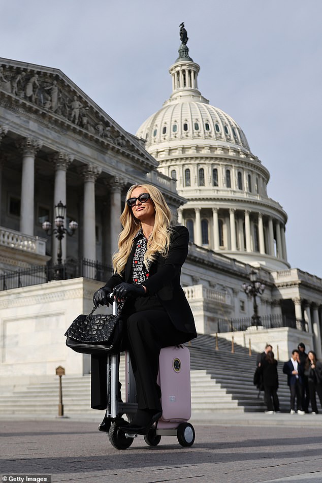 La famosa heredera del hotel Paris Hilton es fotografiada por un miembro de su equipo mientras viaja en un scooter eléctrico Airwheel con equipaje frente al Capitolio de EE. UU.