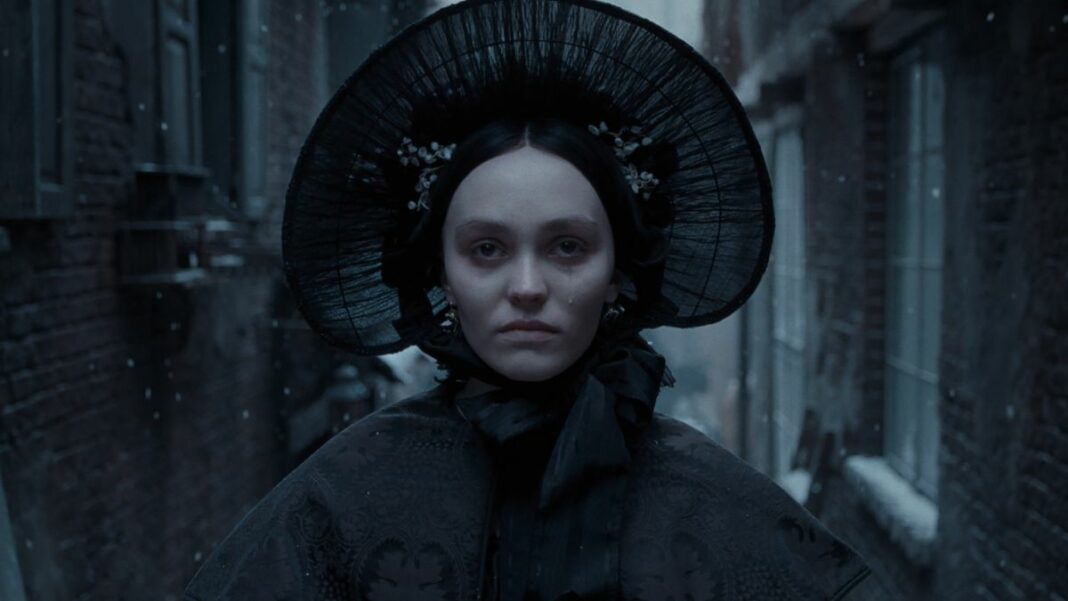 Lily-Rose Depp stares straight ahead somberly in a snowy alley in Nosferatu. 