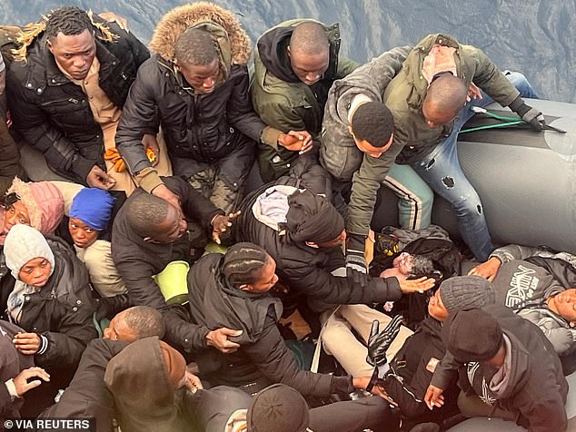 Una sorprendente fotografía tomada desde un barco guardacostas Talia muestra a un migrante acunando a un recién nacido mientras otros en el bote retroceden para dejar espacio al bebé.