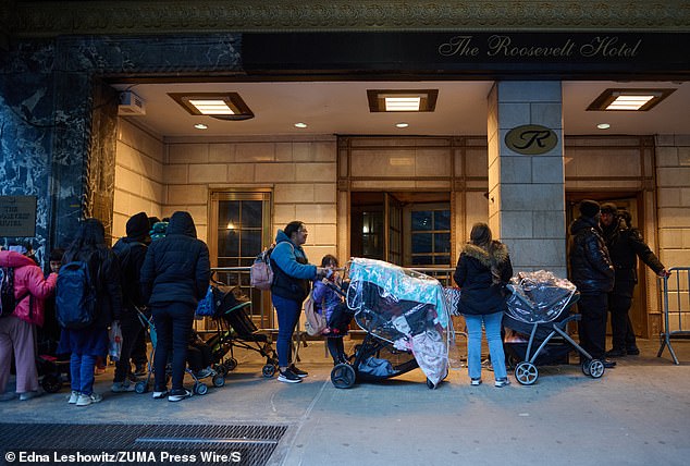 Los migrantes ilegales esperan fuera del Hotel Roosevelt en la ciudad de Nueva York mientras están protegidos allí en fondos federales