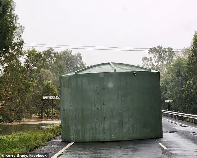 Ha aparecido una foto increíble de un tanque de agua que bloquea la carretera en un arroyo de una milla, cerca de Cardwell, norte de Queensland, después de haber sido recogidos por la fuerza de la corriente