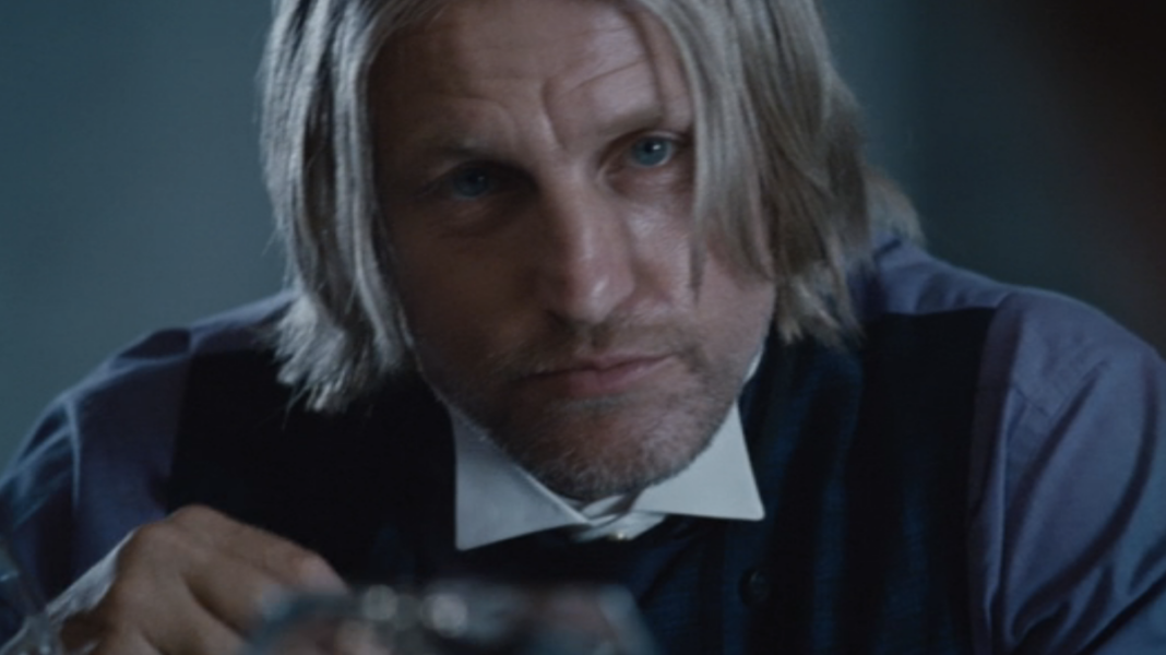 Woody Harrelson as Haymitch looking ahead while having dinner with Effie and the tributes in Hunger Games 