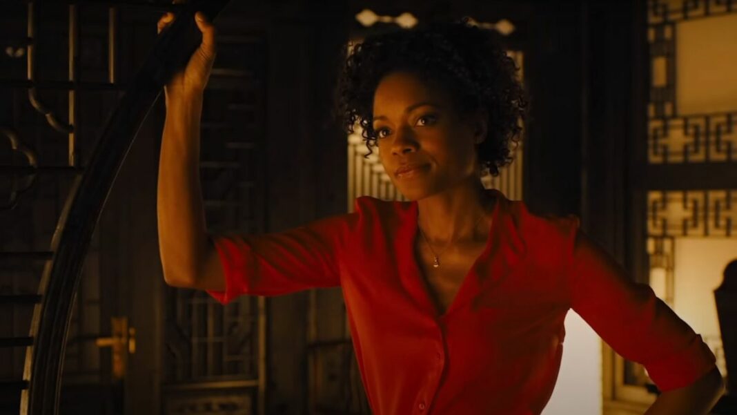 Naomie Harris stands in a doorway in a red dress in Skyfall.