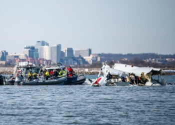 Restos de un avión y helicóptero en el río Potomac con botes de rescate.