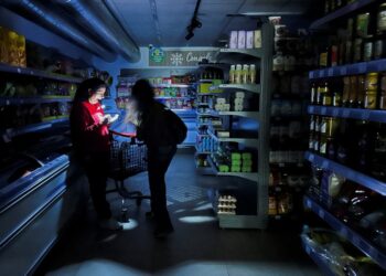Un trabajador ayuda a un cliente con una antorcha en un supermercado durante un corte de energía que llegó a grandes partes de España, en Barcelona, España el 28 de abril de 2025. Reuters/Nacho Doce TPX Imágenes del día