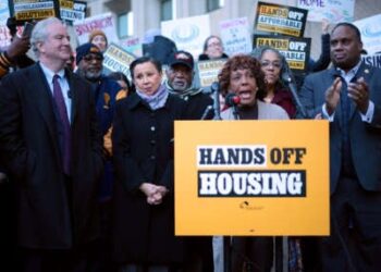 La representante Barbara Lee, rodeada de otros, habla en un podio con un letrero fijo que lee "Manos fuera de la carcasa"