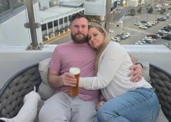 Pareja abrazando el balcón con vistas a la ciudad.