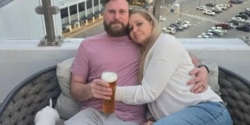 Pareja abrazando el balcón con vistas a la ciudad.