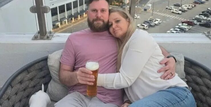 Pareja abrazando el balcón con vistas a la ciudad.