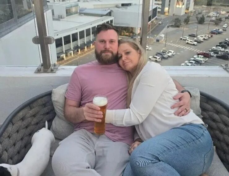 Pareja abrazando el balcón con vistas a la ciudad.