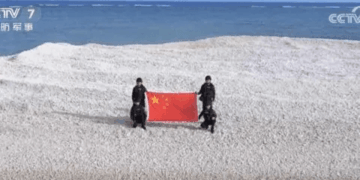 Gente sosteniendo la bandera china en un pequeño banco de arena.