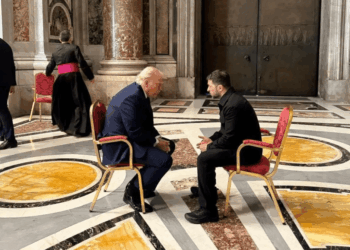 Donald Trump y otro hombre sentados en sillas frente a otros.