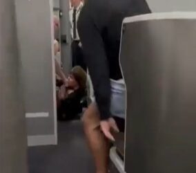 Hombre en pantalones cortos y descalzos ayudando a un pasajero en un avión.