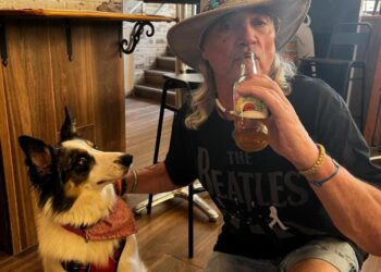 Hombre con perro bebiendo cerveza en un pub.