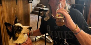 Hombre con perro bebiendo cerveza en un pub.
