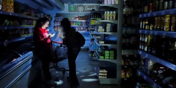 Un trabajador ayuda a un cliente con una antorcha en un supermercado durante un corte de energía que llegó a grandes partes de España, en Barcelona, España el 28 de abril de 2025. Reuters/Nacho Doce TPX Imágenes del día