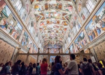 Turistas que ven el techo de la Capilla Sixtine de Michelangelo.