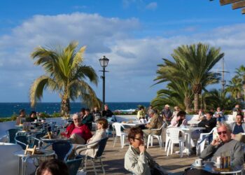 Los clientes sentados en las mesas fuera de un café con vistas al océano.