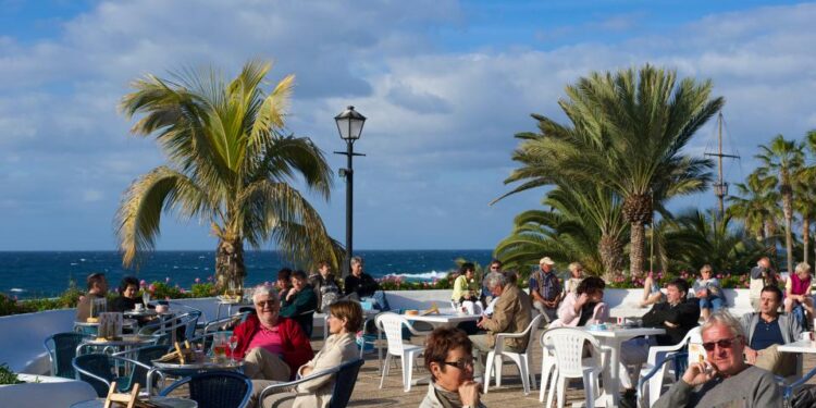 Los clientes sentados en las mesas fuera de un café con vistas al océano.