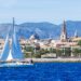 Sailboat en Palma de Mallorca Harbour con ciudad y montañas en el fondo.