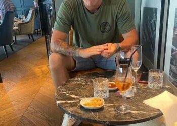 Hombre sentado en una mesa con bebidas y bocadillos.