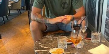 Hombre sentado en una mesa con bebidas y bocadillos.