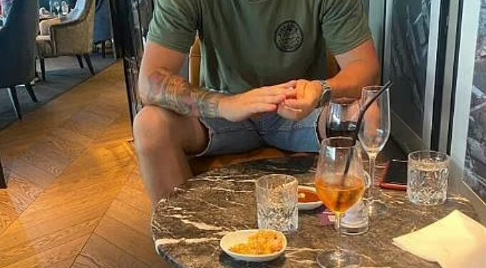 Hombre sentado en una mesa con bebidas y bocadillos.