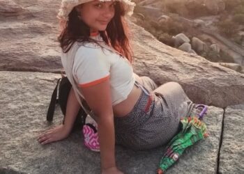 Mujer sentada en una roca con un paraguas.